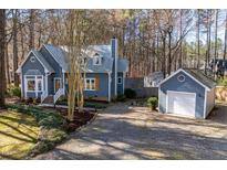 Charming blue home with a detached garage and a gravel driveway nestled amongst mature trees at 1617 Jenkins Rd, Wake Forest, NC 27587