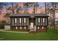 Charming two-story home with gray siding, brick foundation, and a well-manicured lawn at 1911 Stadium Dr, Durham, NC 27705