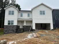 A view of a two-story home with gray stone accents and a two-car garage undergoing construction at 1912 Harrell Cove Ct # 171 Gunnison Cr, Fuquay Varina, NC 27526