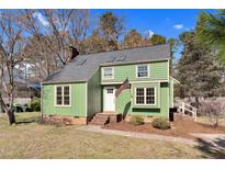 Charming two-story home with green siding, white trim, and an American flag on display at 2321 Ravenhill Dr, Raleigh, NC 27615