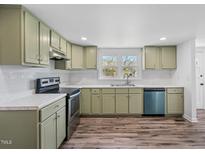 Charming kitchen featuring light green cabinets, stainless steel appliances, and wood-look floors at 608 N 15Th St, Erwin, NC 28339