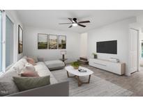 Bright living room featuring a modern sofa, neutral walls, and a ceiling fan at 1016 N Bend Dr, Raleigh, NC 27609