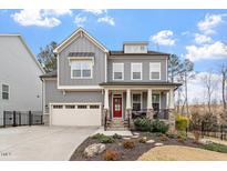 Charming two-story home with gray siding, red door, landscaped yard, and an attached two-car garage at 105 Mystic Quartz Ln, Holly Springs, NC 27540