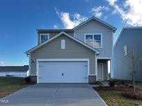 Charming two-story home with a two-car garage, neutral siding, and a well-manicured lawn, set against a bright blue sky at 1121 Solace Way, Rolesville, NC 27571