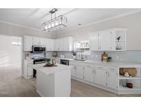 Bright kitchen with white cabinets, an island, and light blue backsplash at 125 Vance Wrenn Rd, Roxboro, NC 27573