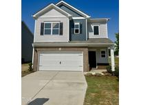 Charming two-story home with brick accents, a white garage door, and manicured landscaping at 184 Bruce Dr, Dunn, NC 28334