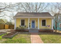 Charming yellow home featuring a cozy front porch with swing and brick walkway at 207 Hargrove St, Durham, NC 27701