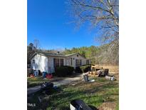 A single-story home with a light-colored exterior and blue shutters, surrounded by an unkempt yard at 2383 Egypt Mountain Rd, Kittrell, NC 27544