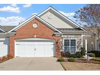 Charming home with a white garage door, brick and siding exterior and a well-maintained lawn at 241 Lifeson Way, Cary, NC 27519