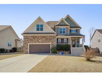 Charming two-story home with a stone-accented facade, inviting front porch and manicured lawn at 440 Stephens Way, Youngsville, NC 27596