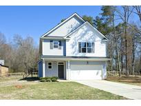 Charming two-story home featuring light blue siding, a one-car garage, and a well-manicured front yard at 704 Vance St, Mebane, NC 27302