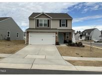 Charming two-story home features a two-car garage, stone accents, and a well-manicured front yard at 745 Little Patch St, Zebulon, NC 27597