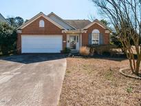 Charming single-story brick home featuring an attached garage and well-maintained front yard at 101 Tiverton Woods Dr, Holly Springs, NC 27540
