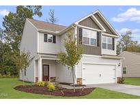 Charming two-story home boasts an attached two-car garage, manicured lawn, and inviting front entrance at 103 Shelfit Trl, Oxford, NC 27565