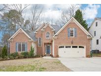Charming brick home with a well-manicured lawn, attached garage, and inviting front entrance at 104 Barnes Spring Ct, Cary, NC 27519