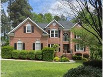 Classic red brick home boasts a manicured lawn, mature trees, and traditional architectural details at 105 Aberson Ct, Cary, NC 27519