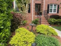 Charming brick home featuring a meticulously maintained front yard with lush greenery and manicured landscaping at 105 Aberson Ct, Cary, NC 27519