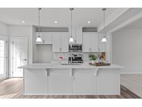 Bright kitchen featuring a large island, pendant lighting, and white cabinetry at 1329 Channing Park Cir, Cary, NC 27519