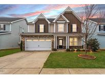 Inviting two-story home boasts a stone facade, two-car garage, and well-manicured lawn at sunset at 2005 Ernesto Ln, Raleigh, NC 27603