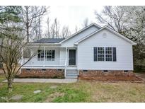 Charming home featuring a covered porch, black shutters, and a well-manicured lawn at 228 Duck Pond Ln, Clayton, NC 27520