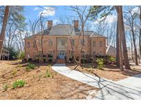 Stately brick home featuring a symmetrical design, mature trees, and well-manicured landscaping at 2602 Vintage Hill Ct, Durham, NC 27712
