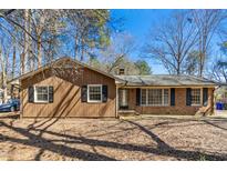 Inviting one-story home featuring a brick and wood facade, surrounded by mature trees and a well-maintained yard at 411 Colony Woods Dr, Chapel Hill, NC 27517