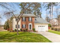 Charming two-story home with a brick and yellow siding, manicured lawn, and an attached garage at 6524 Caverstone Dr, Durham, NC 27713