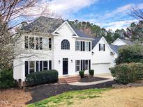 Charming two-story white home with a black roof, blooming trees, and manicured landscaping at 725 Littleleaf Ct, Holly Springs, NC 27540