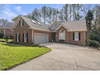 Charming brick home featuring an attached garage and well-manicured front lawn and driveway at 933 Tanworth Dr, Raleigh, NC 27615