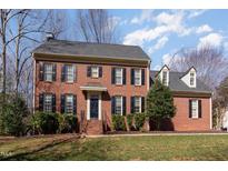 Traditional brick home featuring a landscaped lawn, black shutters, and a classic architectural design at 101 Rustic Wood Ln, Cary, NC 27518