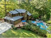Beautiful wooded estate featuring a private pool, hot tub, deck, and attached three-car garage at 1011 Oxbow Crossing Rd, Chapel Hill, NC 27516