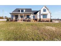 Charming two-story white farmhouse with a welcoming front porch and black trim windows, offering a blend of modern and traditional styles at 107 Crescent Hill Ln, Rougemont, NC 27572