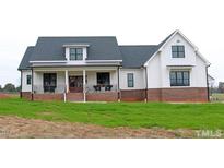 Beautiful two-story modern farmhouse featuring white siding, black trim, and a welcoming front porch at 107 Crescent Hill Ln, Rougemont, NC 27572