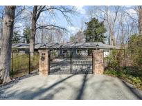 Elegant gated entry with stone pillars and wrought iron leading to a home surrounded by mature trees at 32 Mt. Bolus Rd, Chapel Hill, NC 27514