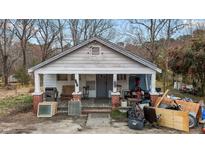 Traditional home with a covered front porch and columns with brick bases needing maintenance and cluttered with various items at 3528 Cheek Rd, Durham, NC 27704