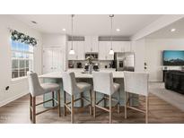 Bright kitchen with stainless steel appliances, white cabinets, and a large center island with bar stool seating at 368 Amber Acorn Ave, Raleigh, NC 27603