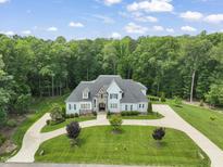 Stunning two-story home featuring blue accents, stone details, a circular driveway, and lush landscaping at 40 Park Meadow Ln, Youngsville, NC 27596