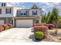 Charming townhome featuring a stone-accented facade, attached garage, and beautifully landscaped front yard with colorful shrubs at 420 Retreat Ln, Wake Forest, NC 27587