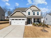 Charming two-story home featuring a two-car garage, a cozy front porch, and stone accents on the facade at 63 Capewood Ct, Garner, NC 27529