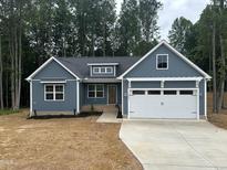 Charming blue single-story home featuring a two-car garage and a well-manicured front yard surrounded by tall trees at 9231 Bear Run Ln, Middlesex, NC 27557