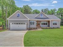 Charming single-story home with gray siding, manicured lawn, and an attached two car garage at 9235 Bear Run Ln, Middlesex, NC 27557