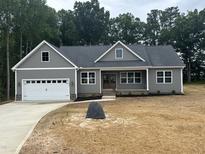 Charming new home boasts a manicured lawn, double-door entryway, and an attached two-car garage at 9235 Bear Run Ln, Middlesex, NC 27557