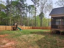 Expansive fenced backyard featuring a play set, perfect for outdoor activities and entertaining at 105 Shawnee Drive, Louisburg, NC 27549