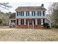 Charming two-story home featuring a brick foundation, gray siding, and classic black shutters at 112 Hartland Ct, Raleigh, NC 27614