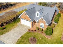Aerial view of brick home with a two-car garage, lush lawn, and mature landscaping at 2 Poplar Ave, Elon, NC 27244