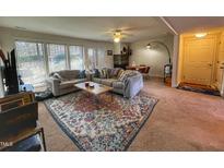 Bright living room featuring a large sectional, brick fireplace, and a stylish area rug at 203 Oak Tree Dr, Chapel Hill, NC 27517