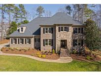 Elegant stone and brick home with a manicured lawn, professional landscaping, and classic shutters at 3905 Grandbridge Dr, Apex, NC 27539