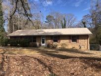 Charming one-story brick home featuring a metal roof, traditional shutters, and a small front porch at 4032 Chaucer Dr, Durham, NC 27705