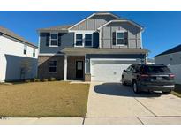 Charming two-story home featuring blue siding, brick accents, and an attached two-car garage at 768 Riguard Way, Wendell, NC 27591