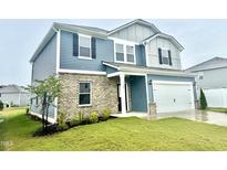 Charming two-story home featuring blue siding, a brick facade, and an attached two-car garage at 768 Riguard Way, Wendell, NC 27591